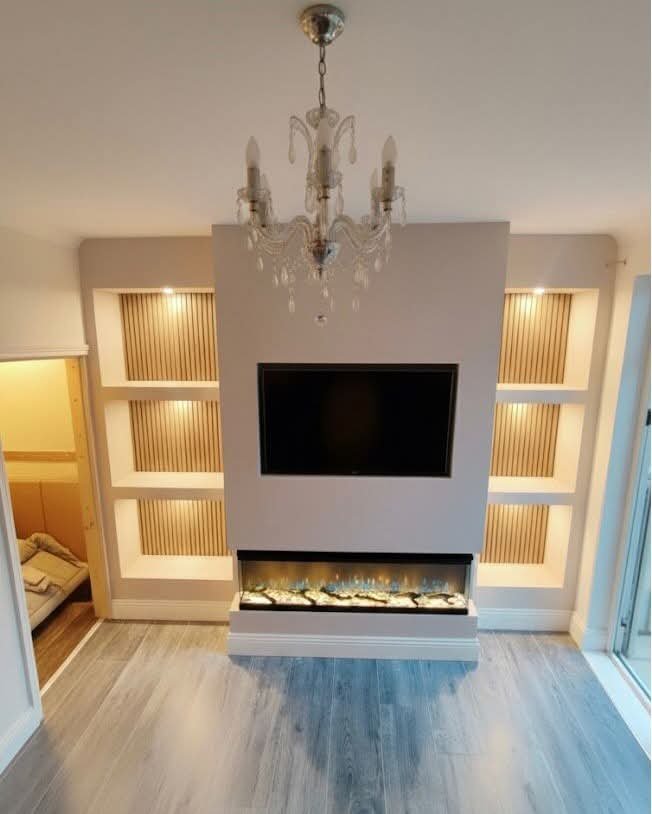 Chandelier above white media wall with 3-sided electric fireplace